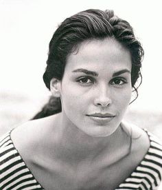 a black and white photo of a woman in striped shirt looking at the camera with her eyes closed