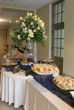 a buffet table filled with lots of food and desserts on top of white clothed tables