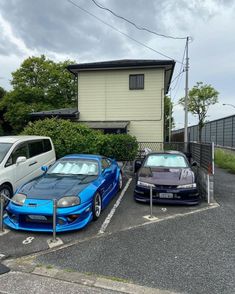 two cars parked in a parking lot next to a house