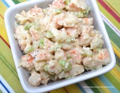 a white bowl filled with macaroni salad on top of a colorful table cloth