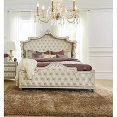 a white bed sitting on top of a carpet covered floor next to a chandelier