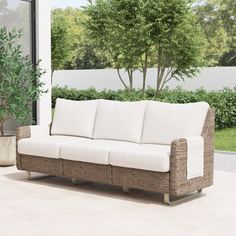 a white couch sitting on top of a patio next to a potted green plant