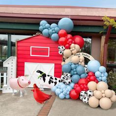 a large number of balloons in front of a red barn