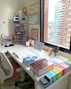 a white desk topped with lots of books next to a window