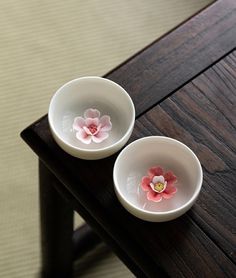 two white bowls with pink flowers in them