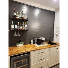 a kitchen with white cabinets and shelves filled with liquor bottles on top of the counter