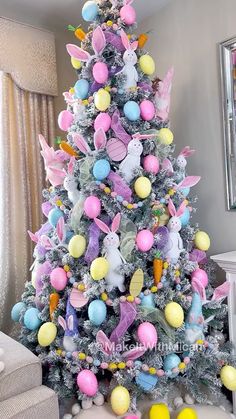 a decorated christmas tree with pastel colored balls and bunny decorations on it in a living room