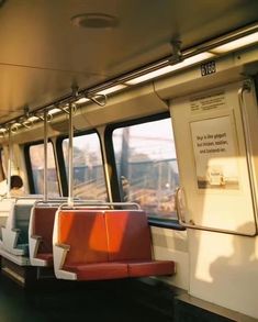 the inside of a train car with red and white seats on each side, looking out the window