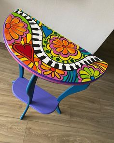 a brightly colored wooden stool with flowers and hearts painted on it