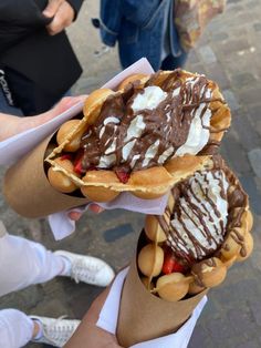 two waffles with ice cream and strawberries on them are being held by people