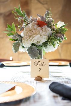 there is a vase with flowers in it and a table number on the card holder