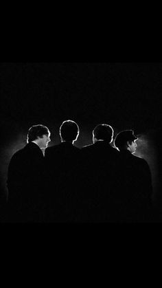 three men are standing in the dark with their backs turned to one another and looking at something