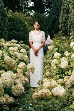 a woman is standing in the middle of some flowers