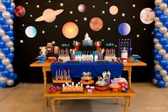 a space themed birthday party with balloons and desserts on the table in front of it