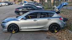 a silver car parked on the side of a road next to a bunch of parked cars