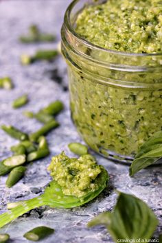 a glass jar filled with green food on top of a table