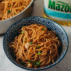 a blue and white bowl filled with noodles next to a container of macaroni