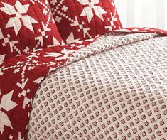 a bed with red and white quilts on it