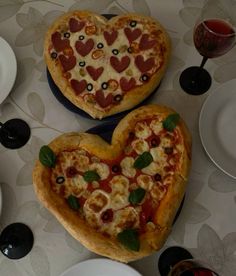 two heart shaped pizzas sitting on top of a table