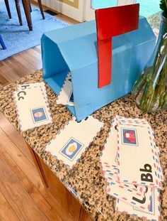 a blue mailbox sitting on top of a counter next to flowers and envelopes