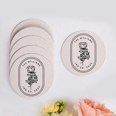 six white coasters with black and white logos on them next to pink flower bouquet