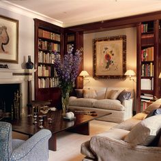 a living room filled with furniture and bookshelves next to a fire place in front of a fireplace