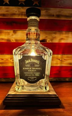 a bottle of jack daniels single barrel whiskey on a wooden table with an american flag in the background