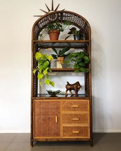 a wicker shelf with plants on top and an animal figurine next to it