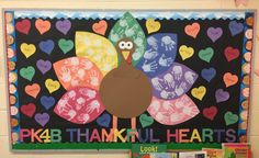 a bulletin board with a turkey made out of handprints and hearts on it