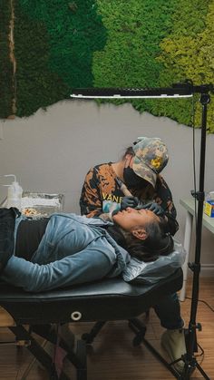 a man laying on top of a black chair next to a woman in front of a green wall