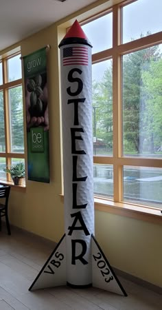 a rocket shaped sign sitting in front of a window