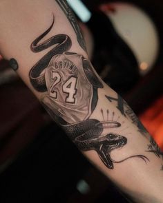 a man's arm with a snake and basketball jersey tattooed on it, along with the number 24