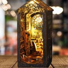 a clock that is inside of a box on a wooden table with lights in the background