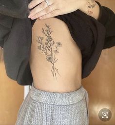 a woman's lower back tattoo with flowers on her ribs and the bottom part of her stomach