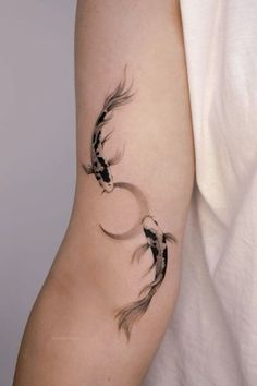 a woman's arm with two black and white koi fish tattoos on it