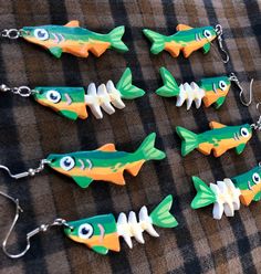 five fish shaped key chains with eyes on them sitting on a plaid tablecloth covered surface