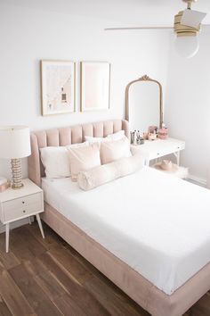 a bedroom with a white bed, pink and gold decor and pictures on the wall