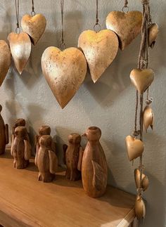 several wooden hearts hanging from hooks on a wall above a mantle with figurines in the shape of animals