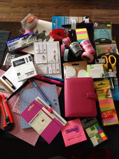 a table topped with lots of different types of office supplies on top of each other