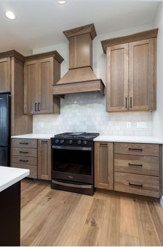 an empty kitchen with wooden cabinets and black stove top oven in the center, along with white counter tops