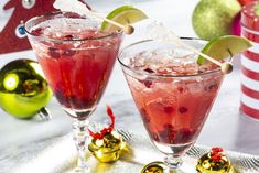 two glasses filled with red liquid and garnished with christmas decorations