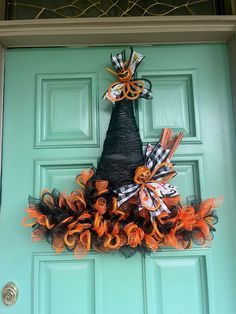 an orange and black wreath is hanging on the front door to give it a unique look