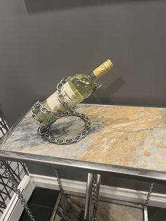 a metal table with a wine bottle on it and a chain around the top that is holding two bottles