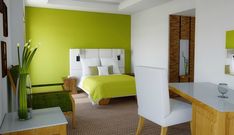 a bedroom with green walls and white furniture in the room, including a bed that has yellow sheets on it