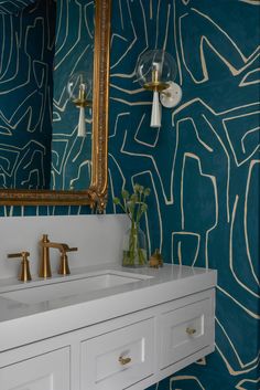 a bathroom with blue and gold wallpaper and two sinks in front of a mirror