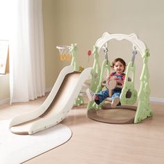 a toddler sitting on a swing set with a basketball hoop