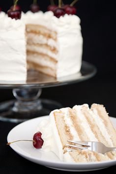 a slice of cake with white frosting and cherries on the top is being held by a fork