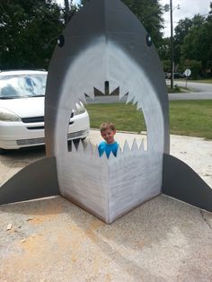 a child in a shark shaped cardboard box