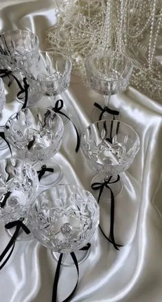 several clear glass vases with black ribbons on a white satin table cloth and beaded chandelier in the background