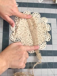 two hands are making doily on a table with scissors and twine around it